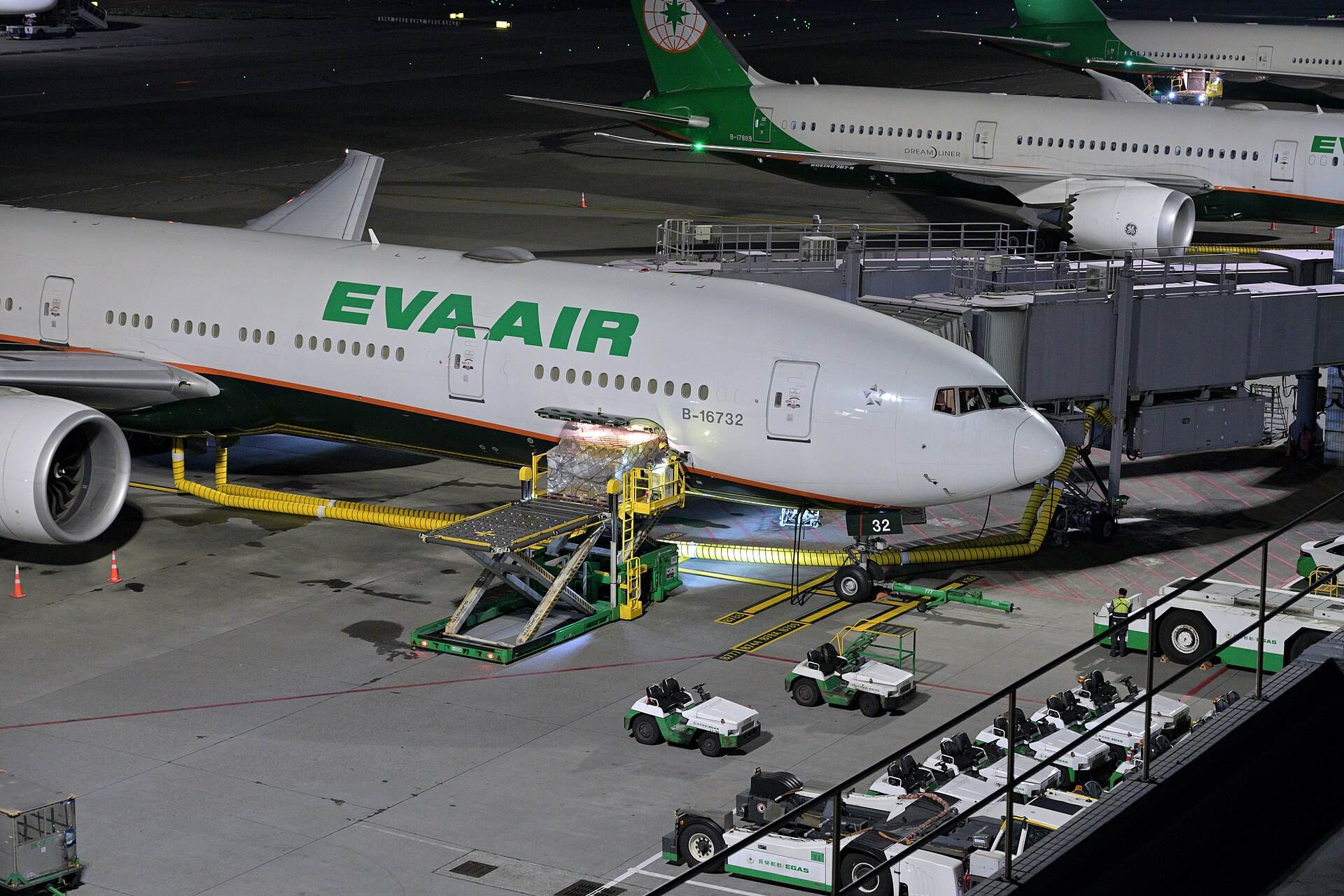 Pallets de carga aérea subiendo a la bodega de un avión, de noche